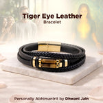 Black leather bracelet with gold accents on a marble surface, with people in the background.