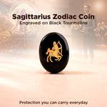 Sagittarius zodiac coin engraved on black tourmaline with blurred people in the background