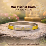 Gold and silver bracelet with yellow accents on a stone surface, featuring 'Om Trishul Kada' text.