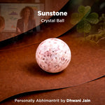 Sunstone crystal ball on a wooden surface with a blurred background of people and plants.