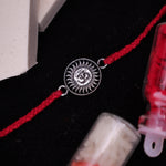 A Rakhi bracelet with a 925 silver Om symbol , displayed on a dark background.
