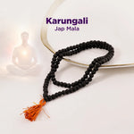 Black Jap Mala with an orange tassel on a white background, featuring the brand 'Karungali'.