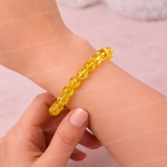 Yellow beaded bracelet on a wrist with a plain background