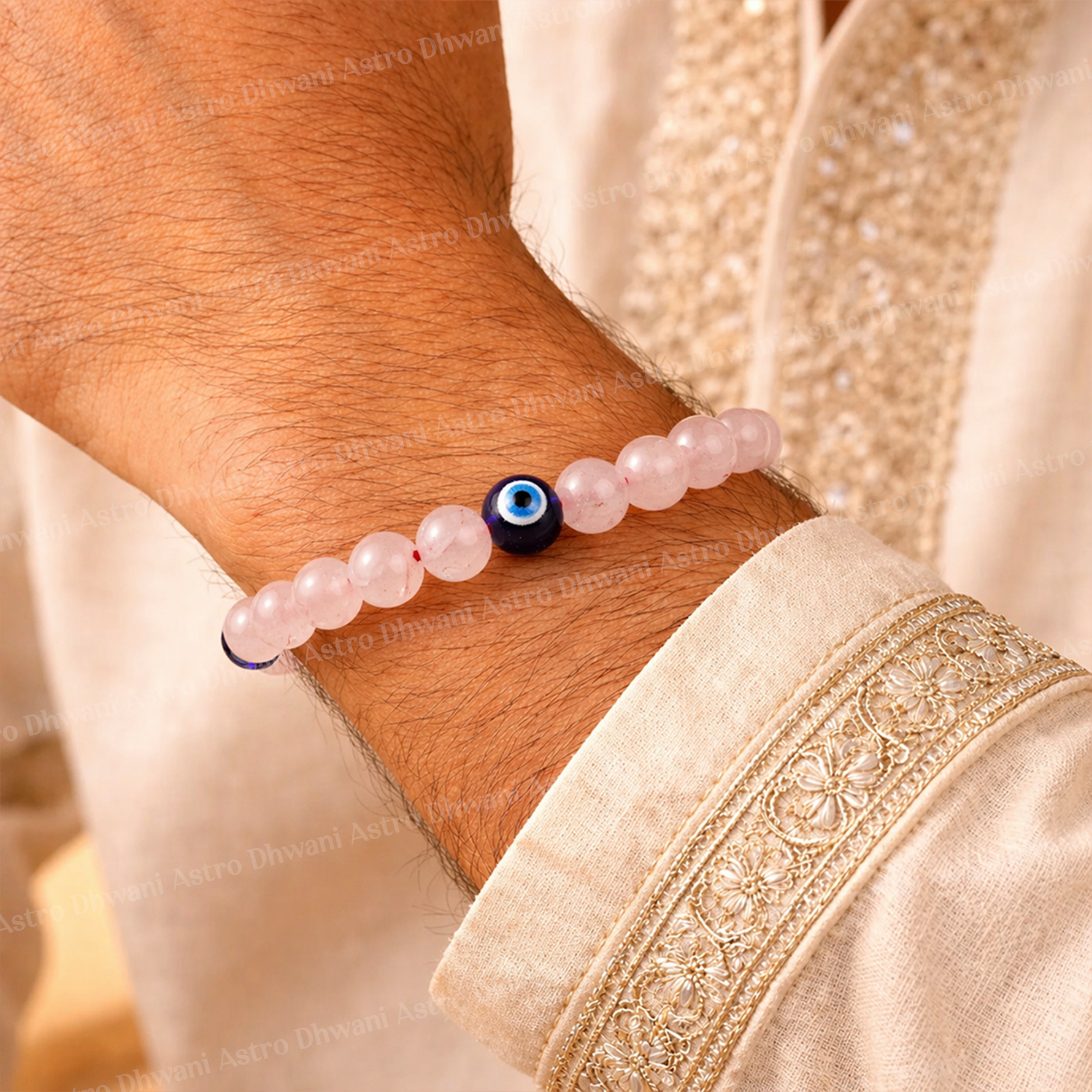 Close-up of a wrist wearing a pink beaded bracelet with a blue and black eye bead, against a beige fabric background.Rose Quartz with Evil Eye Bracelet for Love & Relationship Protection