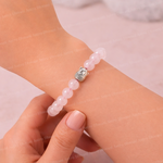 Pink beaded bracelet with a silver owl charm on a wrist against a light background