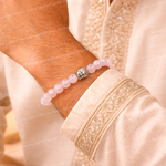 Pink beaded bracelet on a wrist with a beige garment