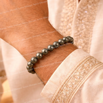 Beaded bracelet on a wrist with a light pink garment in the background
