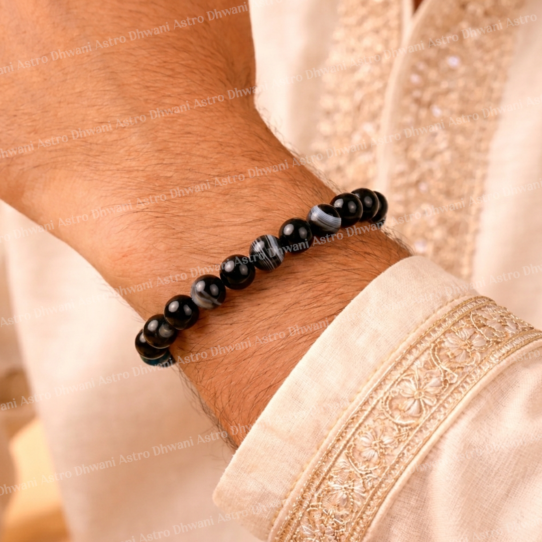 Black beaded bracelet on a wrist with a light pink fabric background