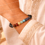 Close-up of a wrist wearing a bracelet with multicolored beads on a light fabric background.