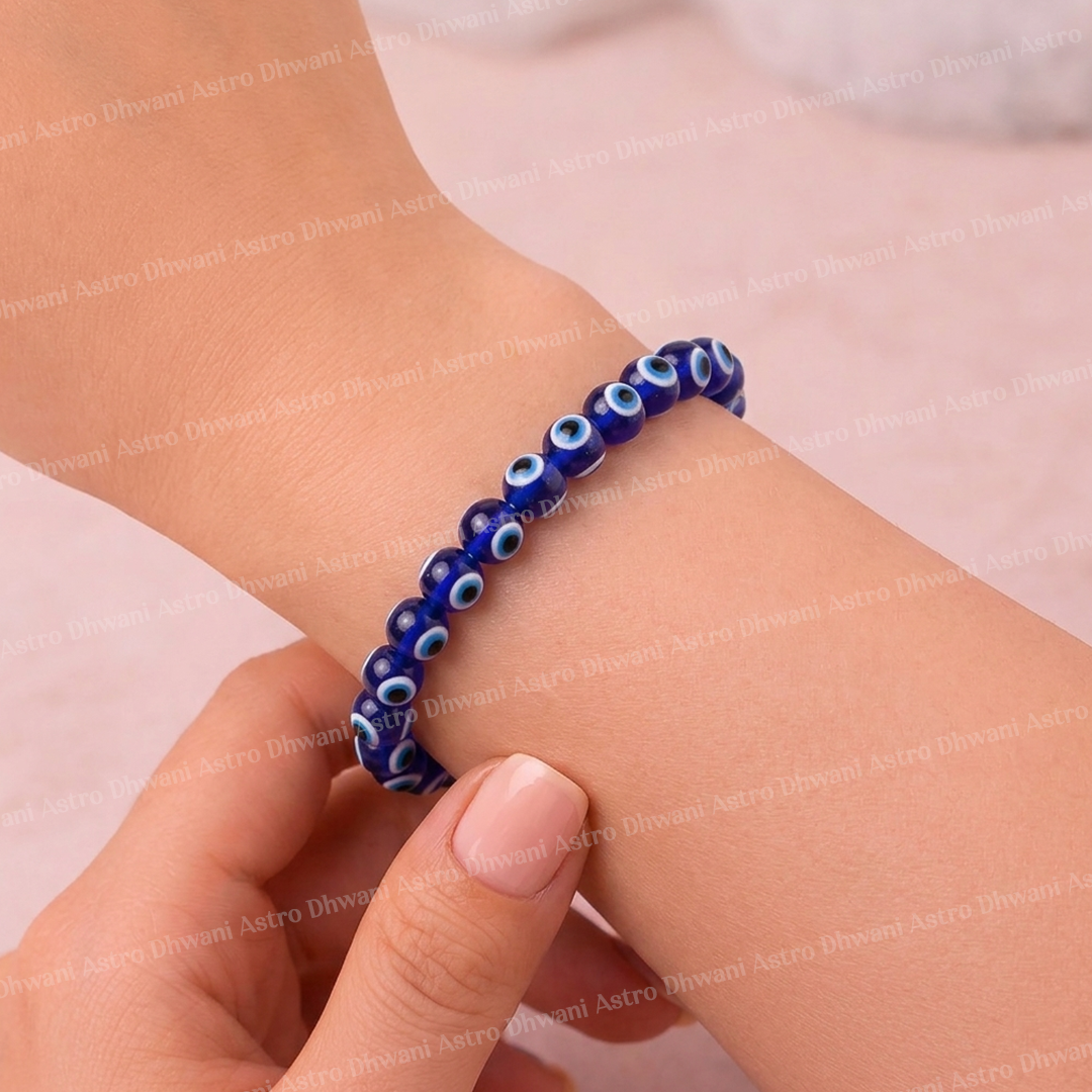 Blue beaded bracelet with eye design on a wrist against a light pink background