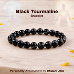 Black tourmaline bracelet on a light wooden surface with decorative elements.