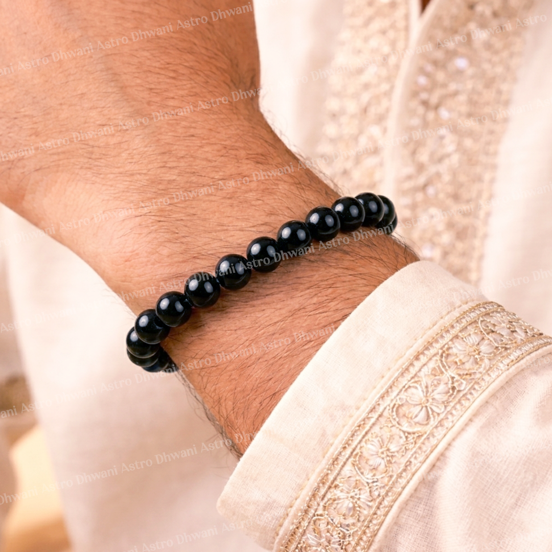 Black beaded bracelet on a wrist with a light pink fabric backgroundBlack Tourmaline Bracelet for Protection, Grounding & Stress Relief