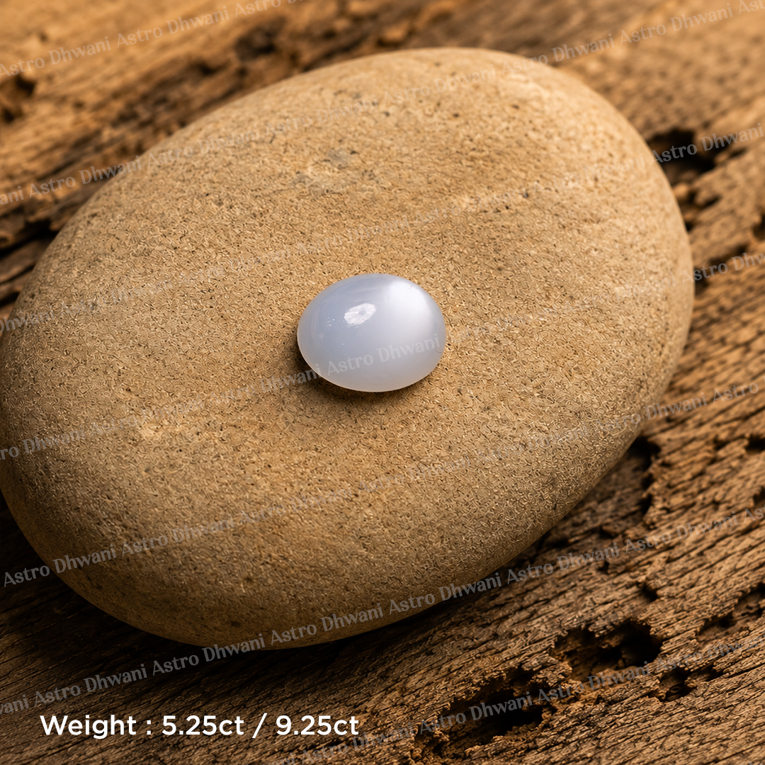A small oval white gemstone with a glossy finish resting on a smooth tan stone, placed on a textured wooden surface. Opal Gemstone – Spiritual Healing Gemstone | Loose Opal Stone for Jewelry, Meditation & Crystal Collection