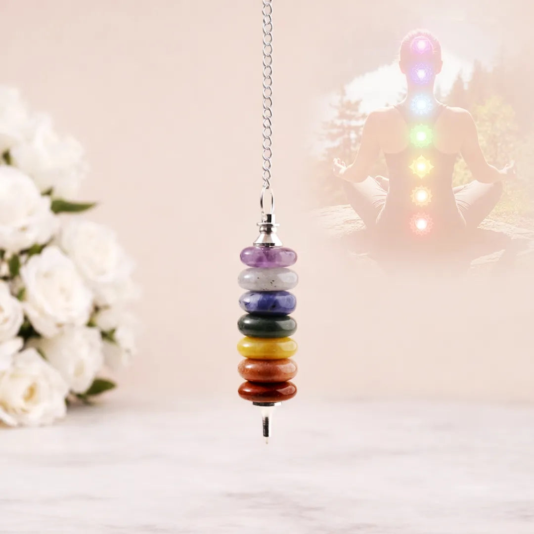Colorful chakra beaded hanging ornament with a blurred background of flowers and a statue.