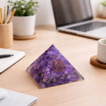 Purple crystal pyramid with a spiral on a desk with a laptop and office supplies.