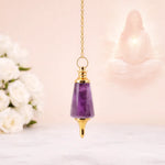 Amethyst pendulum with gold top on a blurred background