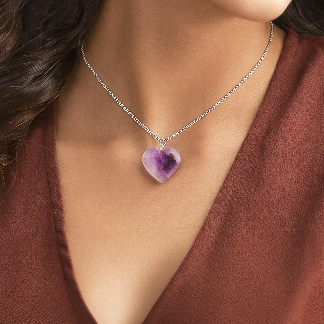 Necklace with a heart-shaped purple pendant worn by a person in a brown top.Amethyst Heart Pendant (Abhimantrit) for Peace & Clarity
