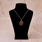 Necklace with a pendant on a black mannequin bust against a beige marble background