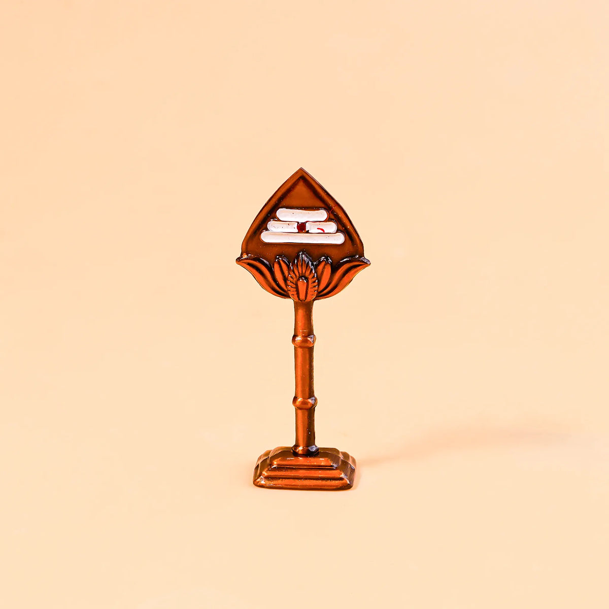 Decorative item with a leaf-shaped top and cylindrical base on a beige background