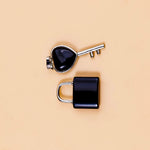 Black padlock and key on a beige background