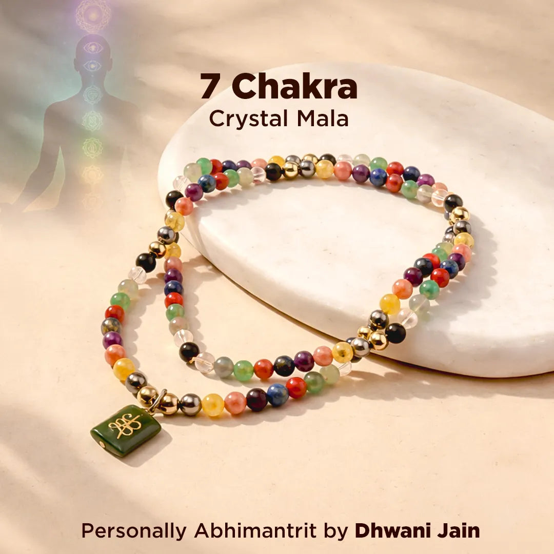 Colorful 7 Chakra Crystal Mala on a white stone with 'Dhwani Jain' branding.