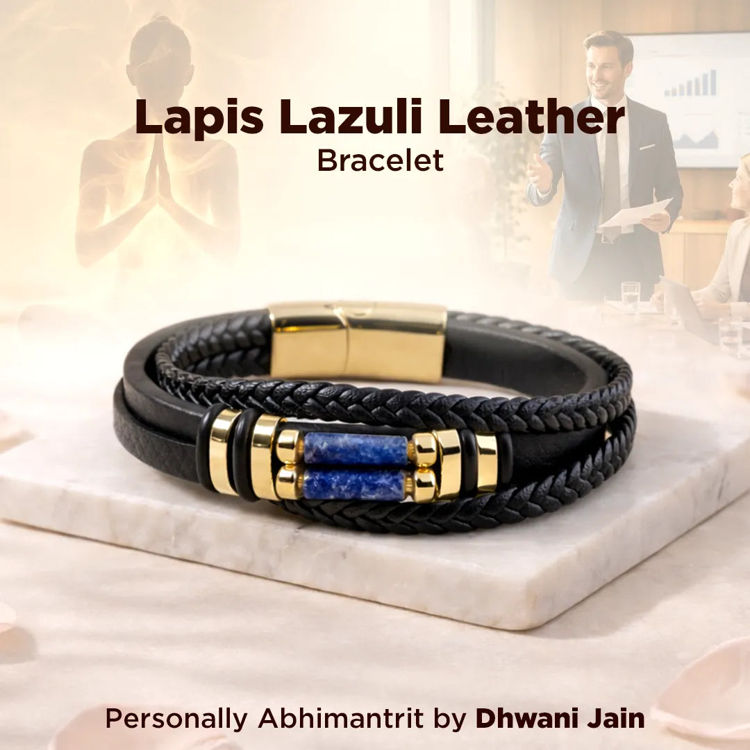 Black leather bracelet with gold accents and blue stones on a marble surface, with a blurred background of people.