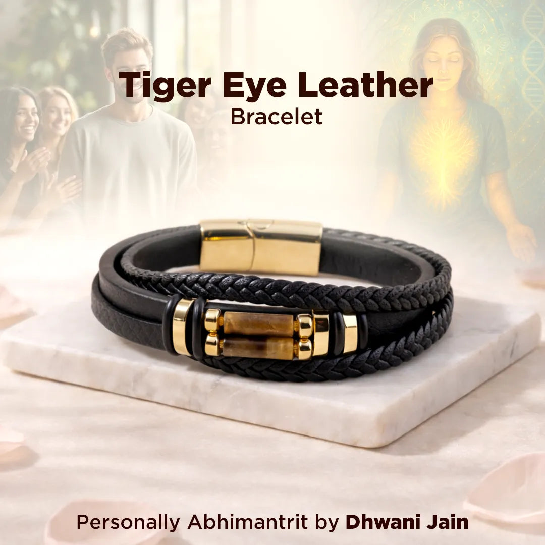 Black leather bracelet with gold accents on a marble surface, with people in the background.