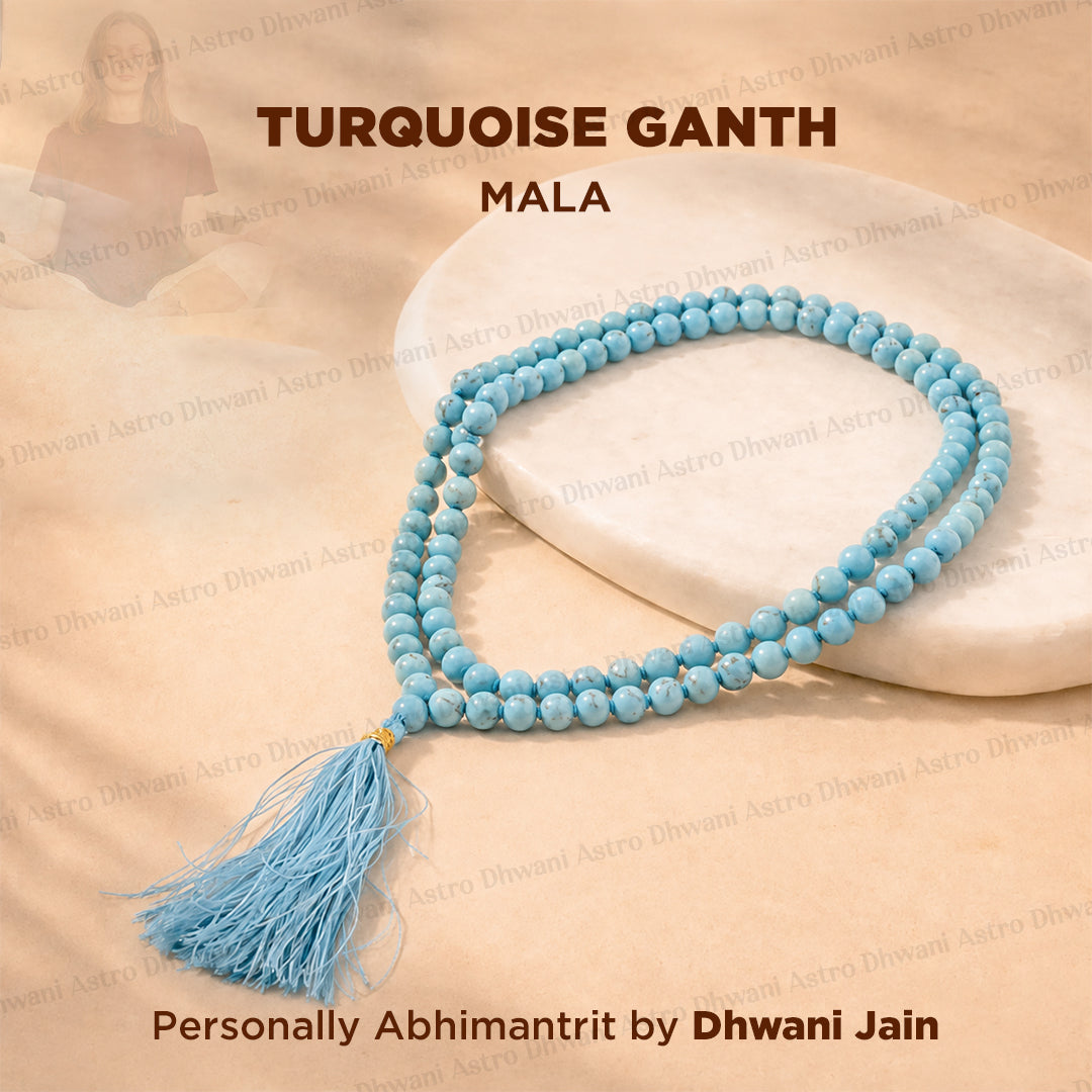 A turquoise mala prayer bead necklace with a matching tassel, displayed on a white stone slab over a beige fabric background.