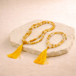 Yellow beaded necklace with tassels on a stone surface