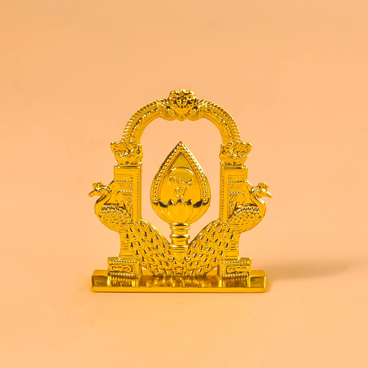 Decorative gold item with intricate designs on a peach background