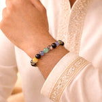 Multicolored beaded bracelet on a wrist with a white garment background
