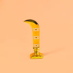 Decorative item resembling a gold sickle on a peach background