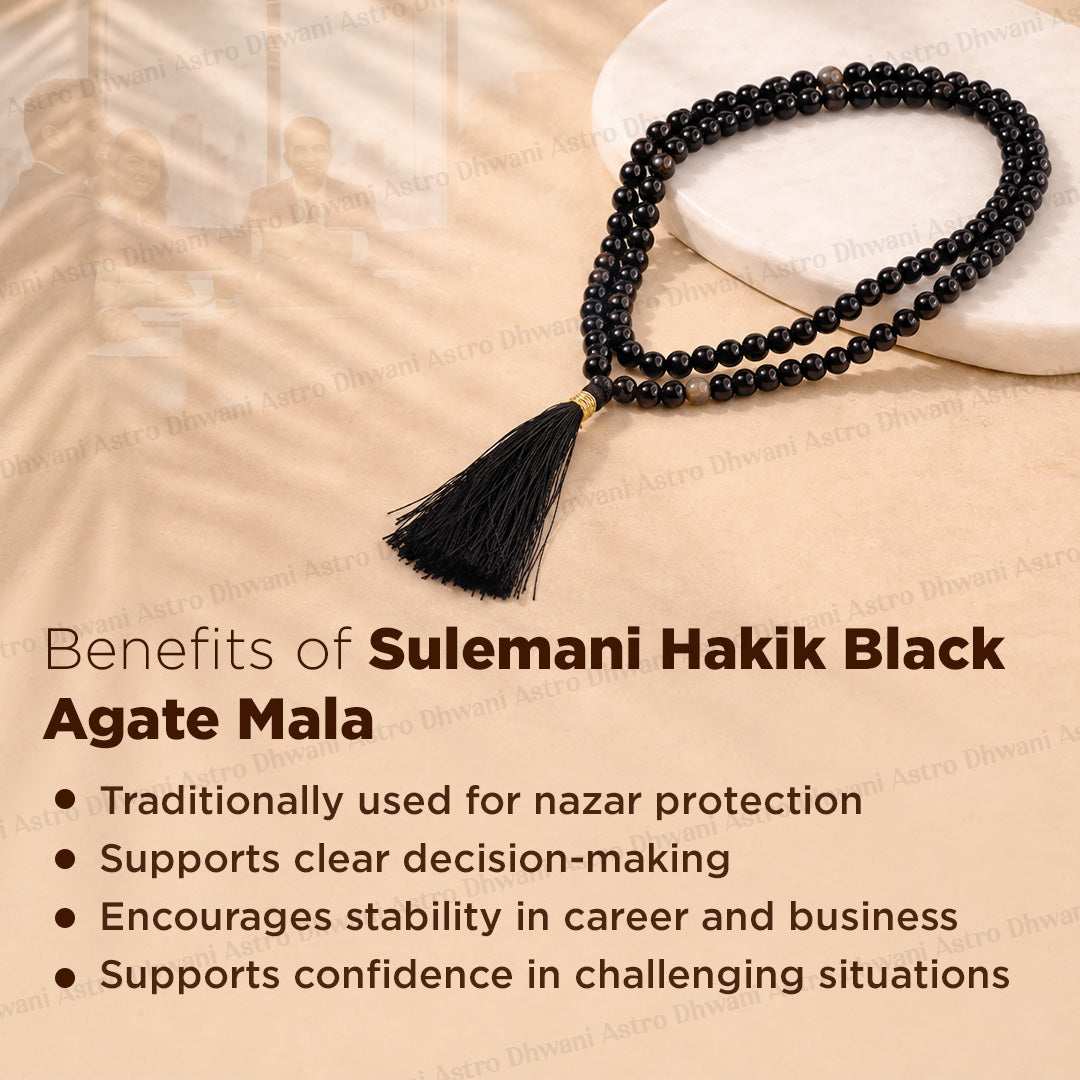 Black agate mala necklace with a black tassel and gold spacer beads, displayed on a beige background with text detailing the benefits of Sulemani Hakik Black Agate Mala.