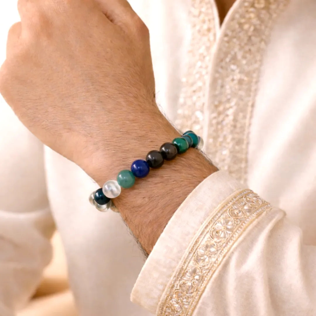 Close-up of a wrist wearing a beaded bracelet with a white garment in the background