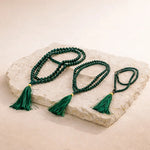 Green beaded necklace with tassels on a stone surface