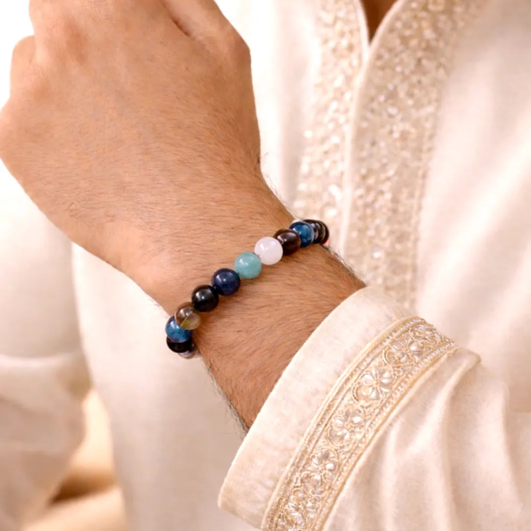 Close-up of a wrist wearing a beaded bracelet with a light-colored garment background