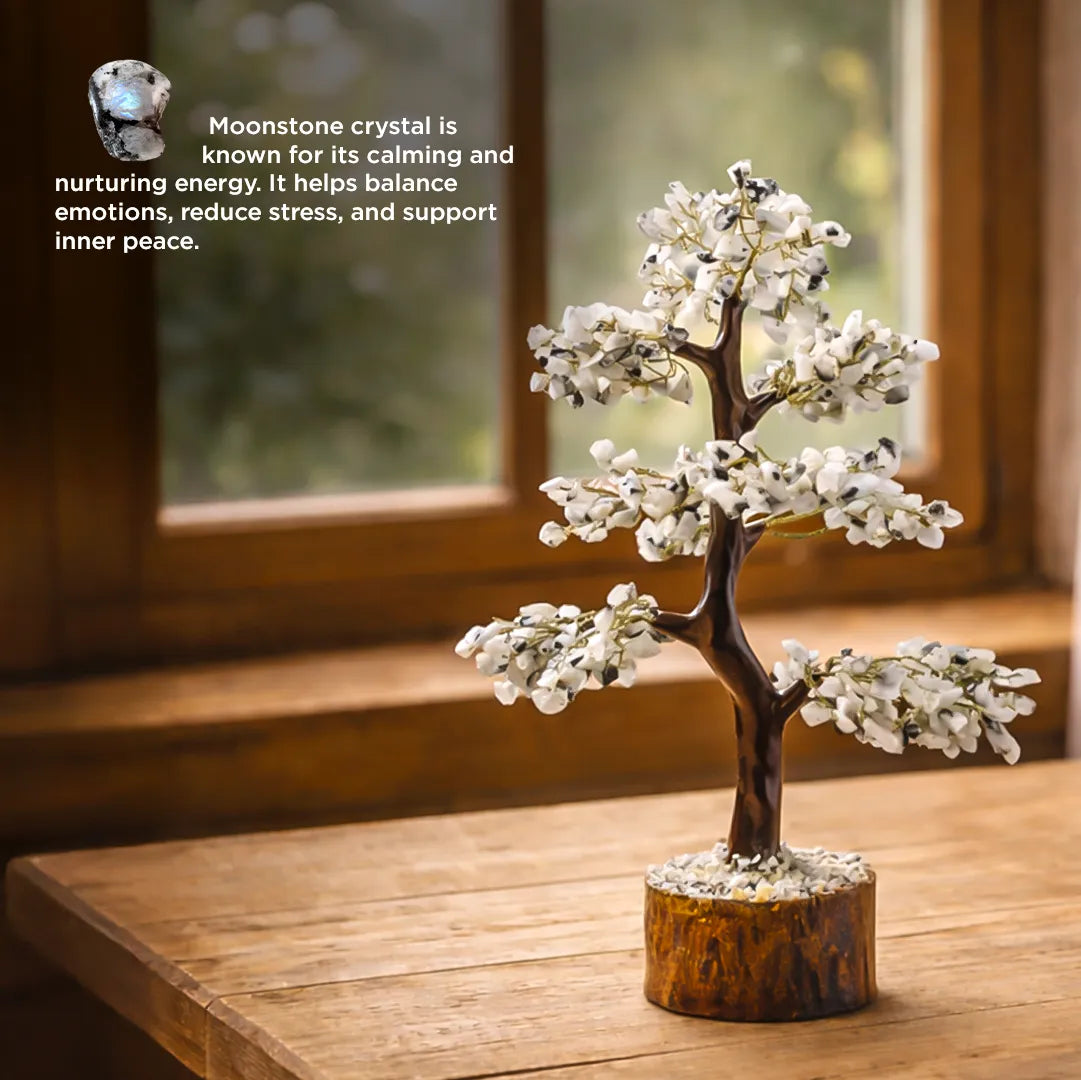 Decorative moonstone crystal tree on a wooden surface with a blurred window background