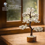 Decorative moonstone crystal tree on a wooden surface with a blurred window background