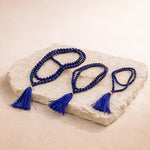 Blue beaded necklace with tassels on a stone surface