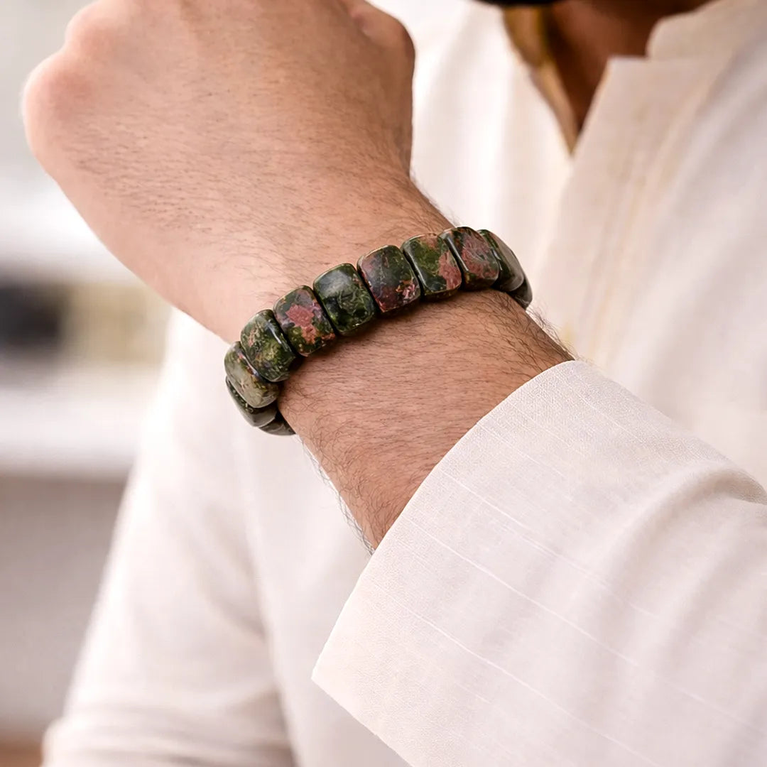 Person wearing a bracelet with green and brown beads on a blurred background