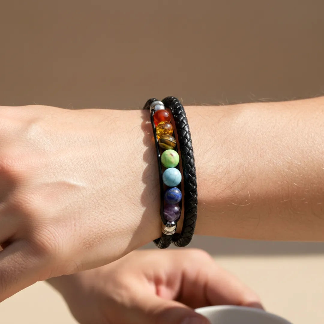 Close-up of a wrist wearing a black braided bracelet with colorful beads on a beige background