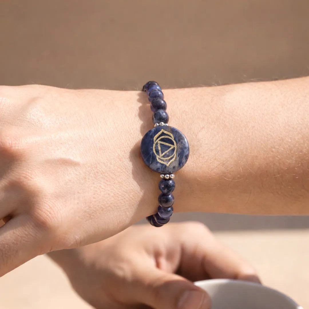 Blue beaded bracelet with a circular design on a wrist against a beige background