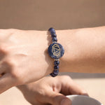 Blue beaded bracelet with a circular design on a wrist against a beige background