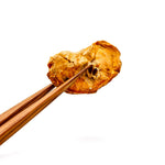 Chopsticks holding a piece of fried food against a white background