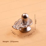 A metallic silver Shiva Lingam shown on a beige background