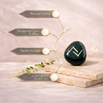 Green crystal stone with gold zodiac symbol on a marble surface, surrounded by decorative elements.
