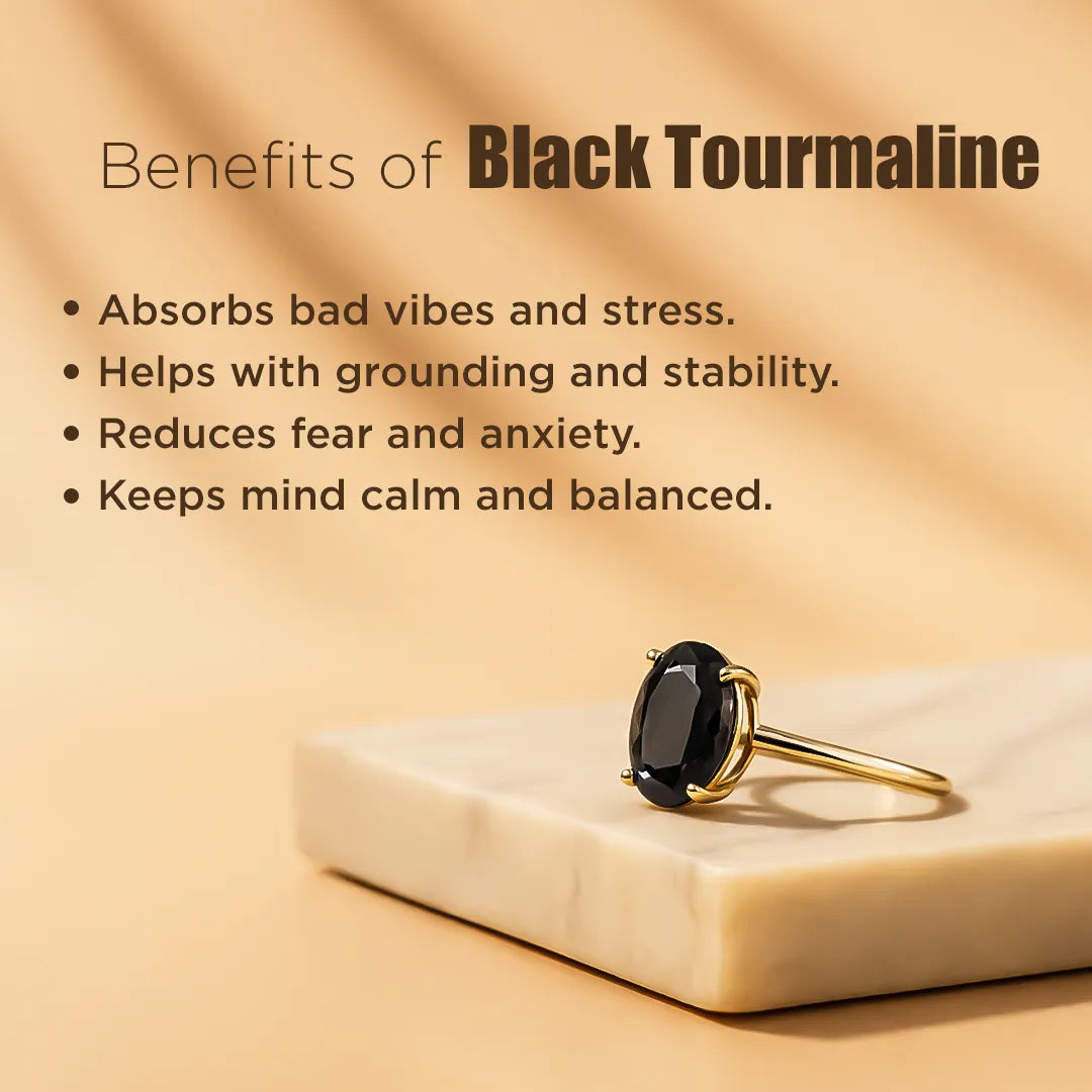Gold ring with black gemstone on a beige surface, with text about black tourmaline benefits.
