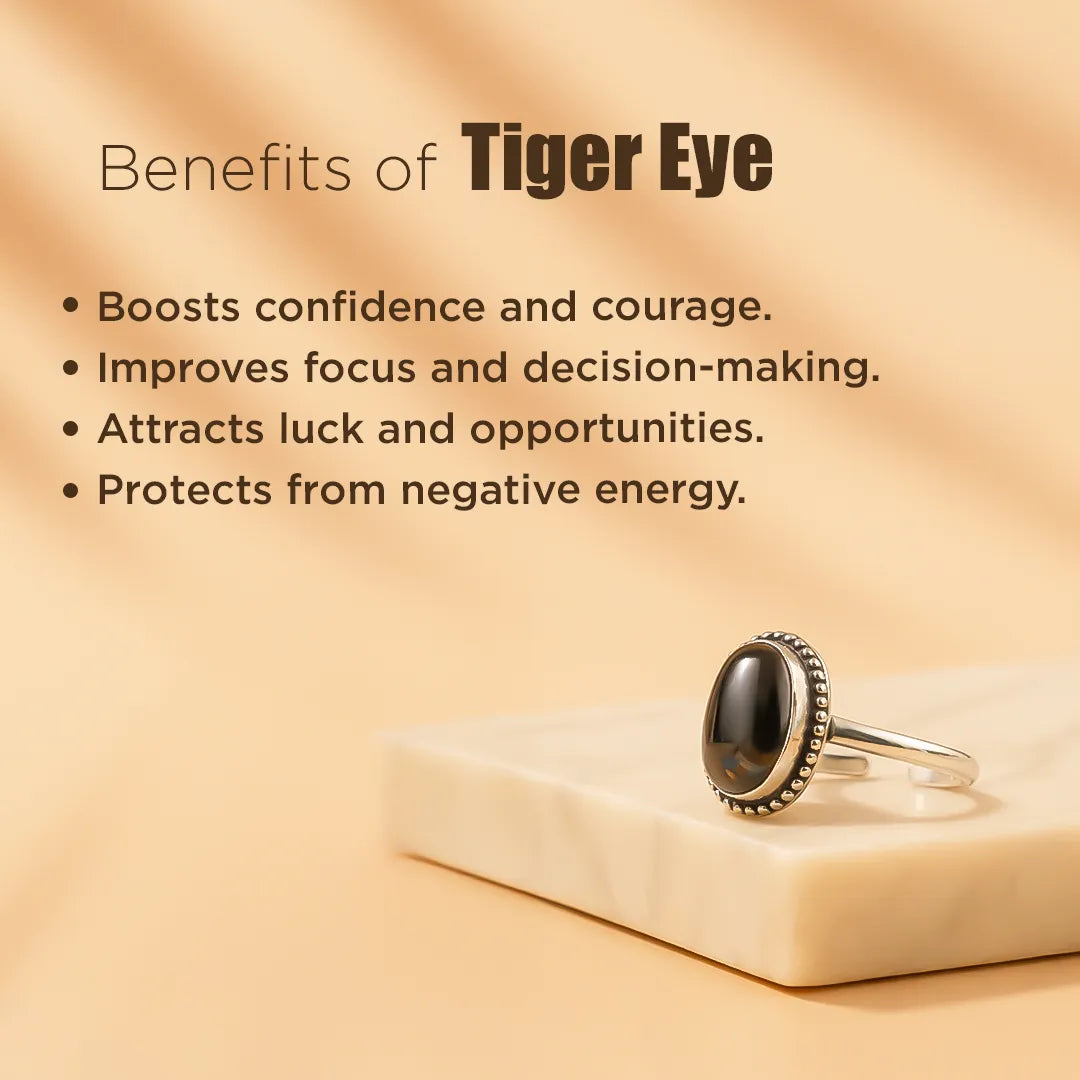 Silver ring with a black stone on a beige surface, featuring text about the benefits of tiger eye.Tiger Eye Ring: Enhances Focus and Decision-Making