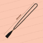 Black beaded mala prayer necklace with a black tassel and gold accent, shown on a peach background with a 25 inches length measurement overlay.