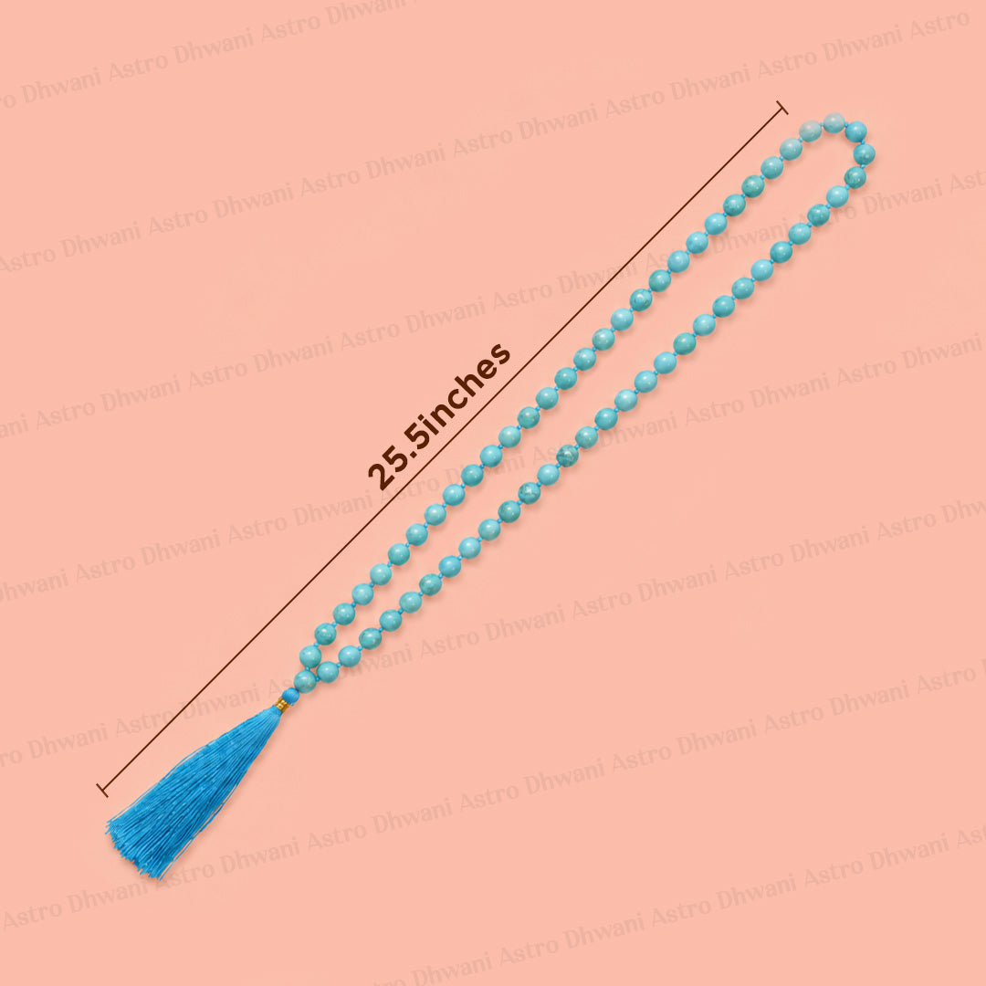 A strand of light blue prayer beads with a matching blue tassel, shown diagonally on a peach background with a measurement line indicating a length of 25.5 inches.एमिथेस्ट जाप माला- अभिमंत्रित और प्रमाणित